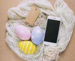 Colorful easter eggs with smartphone and tag on cloth photo