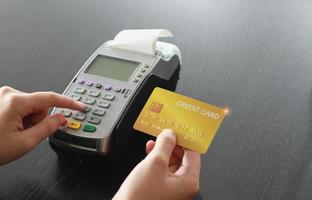 A woman using hand credit card swipe machine for sell products in the shop. Concept of spending via credit card. photo