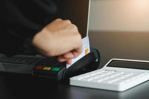 A woman using hand credit card swipe machine for sell products in the shop. Concept of spending via credit card. photo