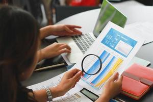 Business woman using magnifying glass to check contract financial documents. photo