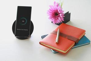 Smartphone wireless charging using wireless charging pad new technology at office. photo