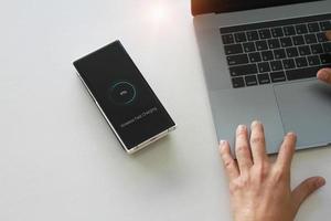 Smartphone wireless charging using wireless charging pad new technology at office. photo