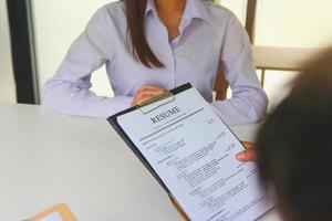 Close-up view of office job interviews with HR personnel holding resume and background checks on applicants with prepared skills.