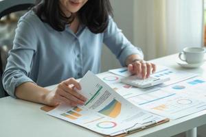 Portrait of a female accountant using a calculator and laptop to calculate balance using graphs for customers. photo