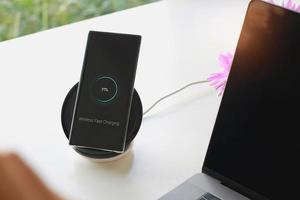 Smartphone wireless charging using wireless charging pad new technology at office. photo