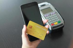 una mujer que usa tarjeta de crédito en un teléfono inteligente para comprar productos en la tienda. concepto de gasto a través de compras en línea con tarjeta de crédito. foto