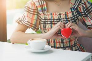 una mujer sostiene un corazón rojo, se pone la mano en el pecho. foto