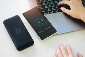 Smartphone wireless charging using wireless charging pad new technology at office. photo