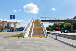 Stairs of a ground pedestrian crossing through a busy city highway on a sunny summer day. photo