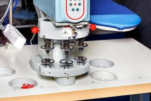 Industrial machine for setting rivets and metal buttons in leather goods and clothing. photo