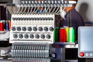 Programmable industrial embroidery machine with multi colored threads and tension system. Closeup, selective focus. photo