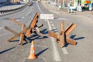 erizos soldados de metal antitanque protectores en la calzada de la carretera de la ciudad y las minas de inscripción en un día soleado. 28.02.22. ktiv. Ucrania. foto