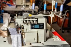 Professional overlock machine in the sewing shop of a factory for sewing clothes. Closeup. photo