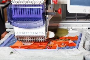 Computerized industrial embroidery machine with multicolored threads, close-up, selective focus. photo