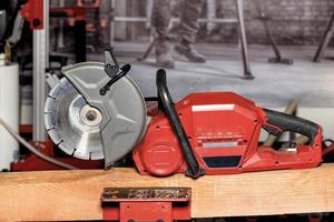 An electric cutter with a diamond wheel lies on a wooden beam against the background of a construction site in blur. photo