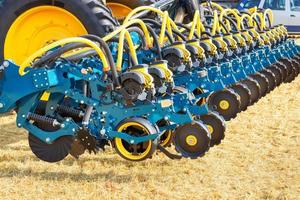 el mecanismo de rueda de una sembradora de varias hileras como enganche a un tractor en el fondo de un campo agrícola. foto