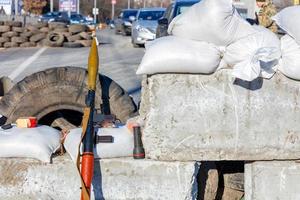 A hand grenade launcher at a checkpoint made of reinforced concrete blocks against the backdrop of a city street in Kyiv. photo