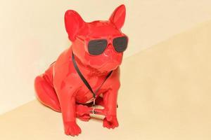 A cool figurine of a red guard dog with black glasses and a hidden surveillance camera on his forehead. photo