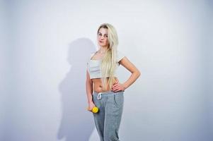 Blonde sporty girl with yellow dumbbell posed at studio against white background. photo