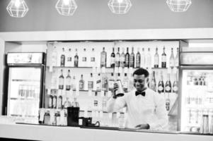 camarero afroamericano en el bar con agitador. preparación de bebidas alcohólicas. foto