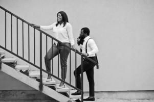 Stylish african american couple in formal wear. Romantic couple in love dating against yellow wall in stairs. photo