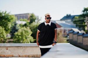 Stylish arabian muslim boy with originally hair and sunglasses posed on streets at roof. photo