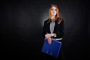 retrato de una mujer de negocios pelirroja con blusa a rayas, gafas y una chaqueta con una carpeta azul. foto