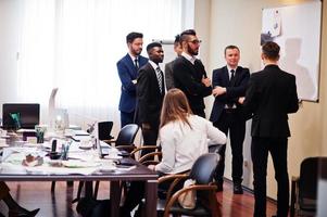 el equipo de negocios multirracial se dirige a la reunión alrededor de la mesa de juntas y escribe el plan a bordo. foto