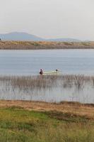 silhouette of fisherman on wood boat at lake. photo