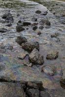 petróleo crudo en agua de mar y reflejo del arco iris foto