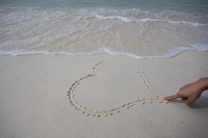 corazones dibujados en la arena de una playa foto