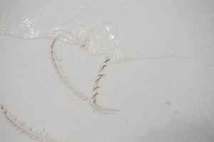 corazones dibujados en la arena de una playa foto