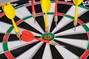 Red and yellow dart arrows hitting in the target center of dartboard. Success hitting target aim goal achievement concept photo