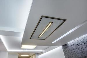 halogen spots lamps on suspended ceiling and drywall construction in in empty room in apartment or house. Stretch ceiling white and complex shape. photo