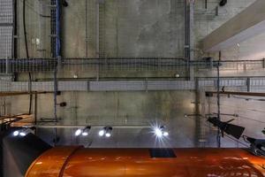 looking up on gray concrete ceiling with halogen spots and edison lamps in loft office room with air conditioning and orange ventilation pipe photo