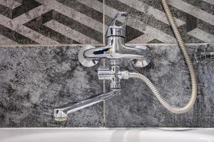 water tap sink with faucet in expensive loft bathroom. detail of a corner shower cabin with wall mount shower attachment photo