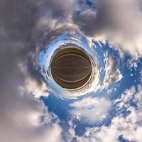 Little planet transformation of spherical panorama 360 degrees. Spherical abstract aerial view in field with awesome beautiful clouds. Curvature of space. photo