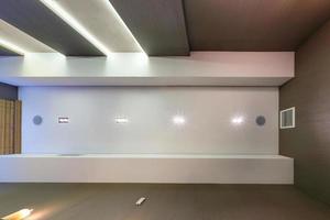 looking up on suspended ceiling with halogen spots lamps and drywall construction in empty room in apartment or house. Stretch ceiling white and complex shape. photo