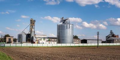 Modern Granary elevator. Silver silos on agro-processing and manufacturing plant for processing drying cleaning and storage of agricultural products, flour, cereals and grain. photo