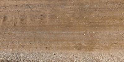 view from above on surface of gravel road with car tire tracks photo