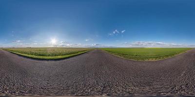 Full spherical seamless panorama 360 degrees angle view on old no traffic asphalt road among fields in evening  before sunset with clear sky in equirectangular projection, VR AR content photo