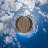 Little planet transformation of spherical panorama 360 degrees. Spherical abstract aerial view in field with awesome beautiful clouds. Curvature of space. photo