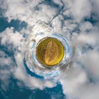 Little planet transformation of spherical panorama 360 degrees. Spherical abstract aerial view in field with awesome beautiful clouds. Curvature of space. photo