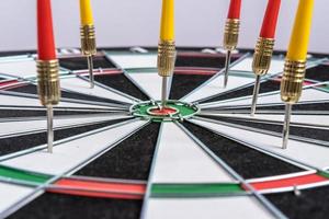 Red and yellow dart arrows hitting in the target center of dartboard. Success hitting target aim goal achievement concept photo