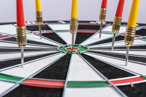 Red and yellow dart arrows hitting in the target center of dartboard. Success hitting target aim goal achievement concept photo