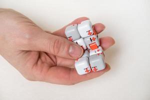 coloridos dedos antiestrés fidget cubo juguete en mano sobre fondo blanco. desarrollo de habilidades motoras finas de los dedos de los niños foto