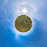 Little planet transformation of spherical panorama 360 degrees. Spherical abstract aerial view in field with awesome beautiful clouds. Curvature of space. photo