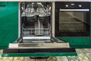 Interior of the modern kitchen with opened Dishwasher in loft flat apartment in minimalistic style with green color photo