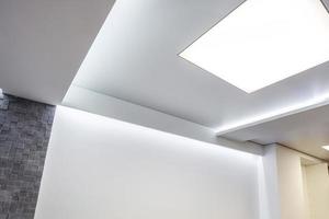 halogen spots lamps on suspended ceiling and drywall construction in in empty room in apartment or house. Stretch ceiling white and complex shape. photo