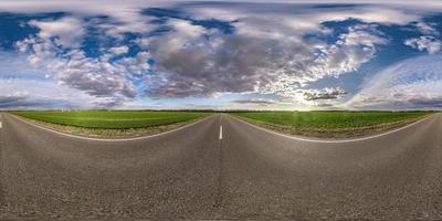 Full spherical seamless panorama 360 degrees angle view on no traffic asphalt road among fields in evening  before sunset with cloudy sky. 360 panorama in equirectangular projection, VR AR content photo